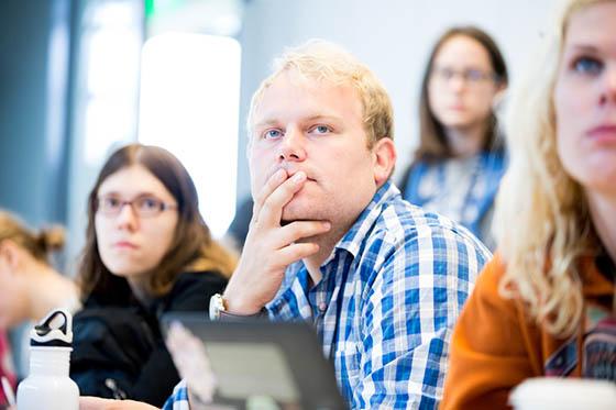 Photo of a male Chatham University student seated next to classmates, paying attention to an unseen lecturer